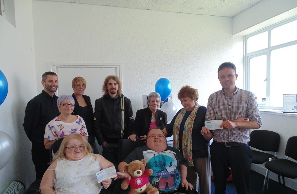 Accessible News volunteers presenting cheques to representatives from the British Lung Foundation and the Brittle Bone Society